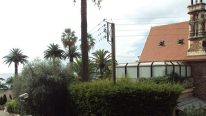 A residential area with a house featuring a tiled roof and a stone facade. There are palm trees and a parked car visible. -  Beautiful Cannes Apartment (Cannes)