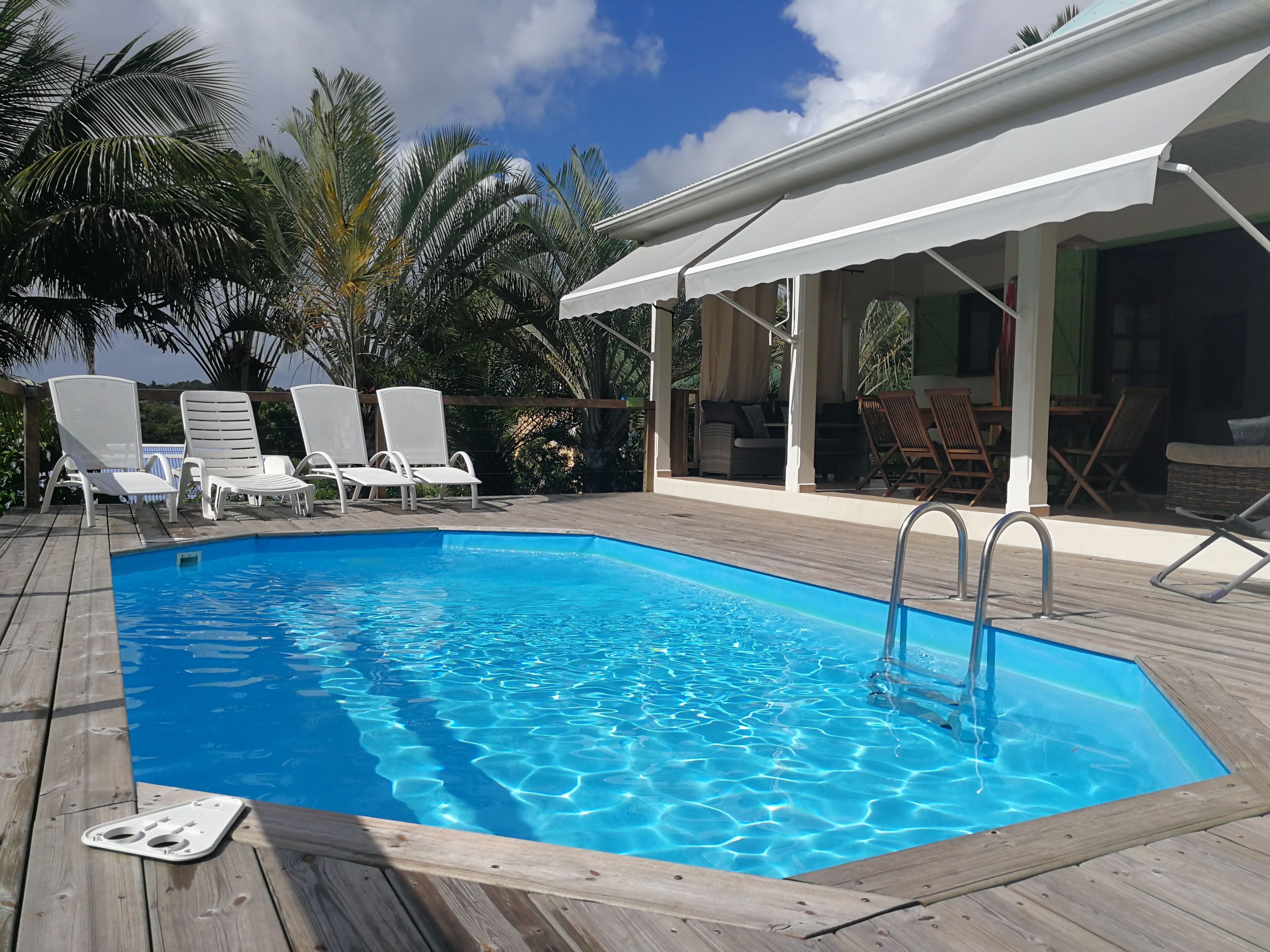 A swimming pool with lounge chairs and a covered seating area.
