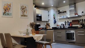 A modern kitchen with white cabinets, stainless steel appliances, and a dining area with a table and chairs. - Excellent Apartment totally renovated, Paris 5th arrondissement (Paris)