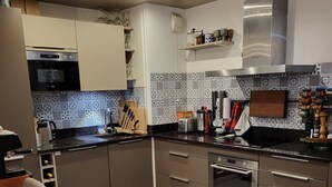 A modern kitchen with grey tiled backsplash, stainless steel appliances, and wooden cabinets. - Excellent Apartment totally renovated, Paris 5th arrondissement (Paris)