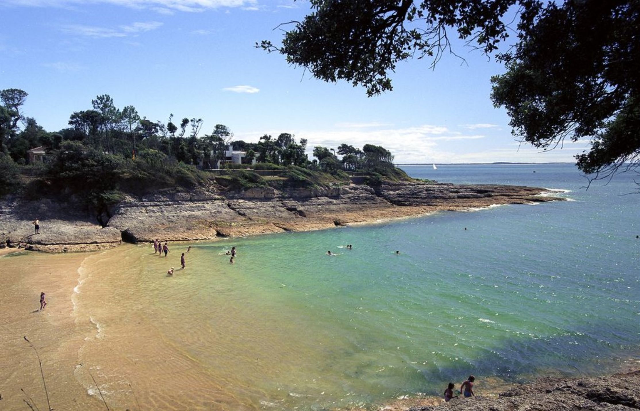 A coastal beach with clear waters and rocky terrain.