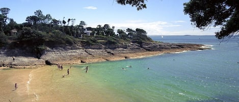 Une plage côtière aux eaux cristallines et au paysage rocheux.