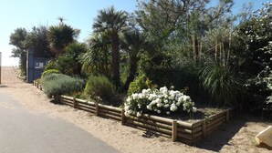 A paved road with a wooden fence and a flower bed with white flowers. - Garden floor with mezzanine close to all amenities and the center (Portiragnes)