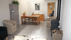 En kompakt opholdsstue med spiseplads, sofa, stol, lampe, skab og et tæppe.