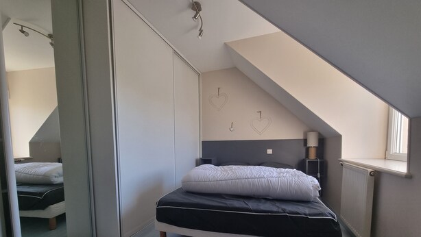 Une chambre à coucher avec un lit, une porte coulissante, un radiateur et une fenêtre.
