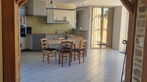 Een keuken met een eettafel en stoelen, houten balken en een betegelde vloer.