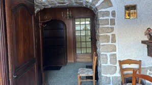 Una habitación con un arco de piedra, una puerta de madera y una pequeña mesa con una estatua.