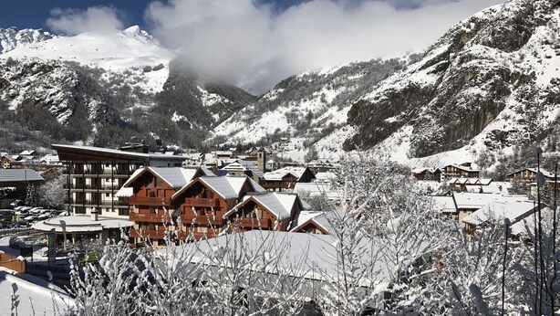 Un pueblo cubierto de nieve con edificios de madera y una estación de esquí.