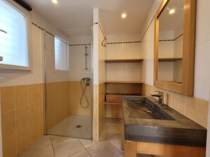 Een badkamer met een douchecabine van glas, een wastafel met spiegel en betegelde wanden.
