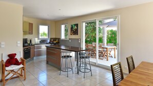 Una cocina moderna con una isla central, taburetes de bar y un comedor con mesa y sillas.