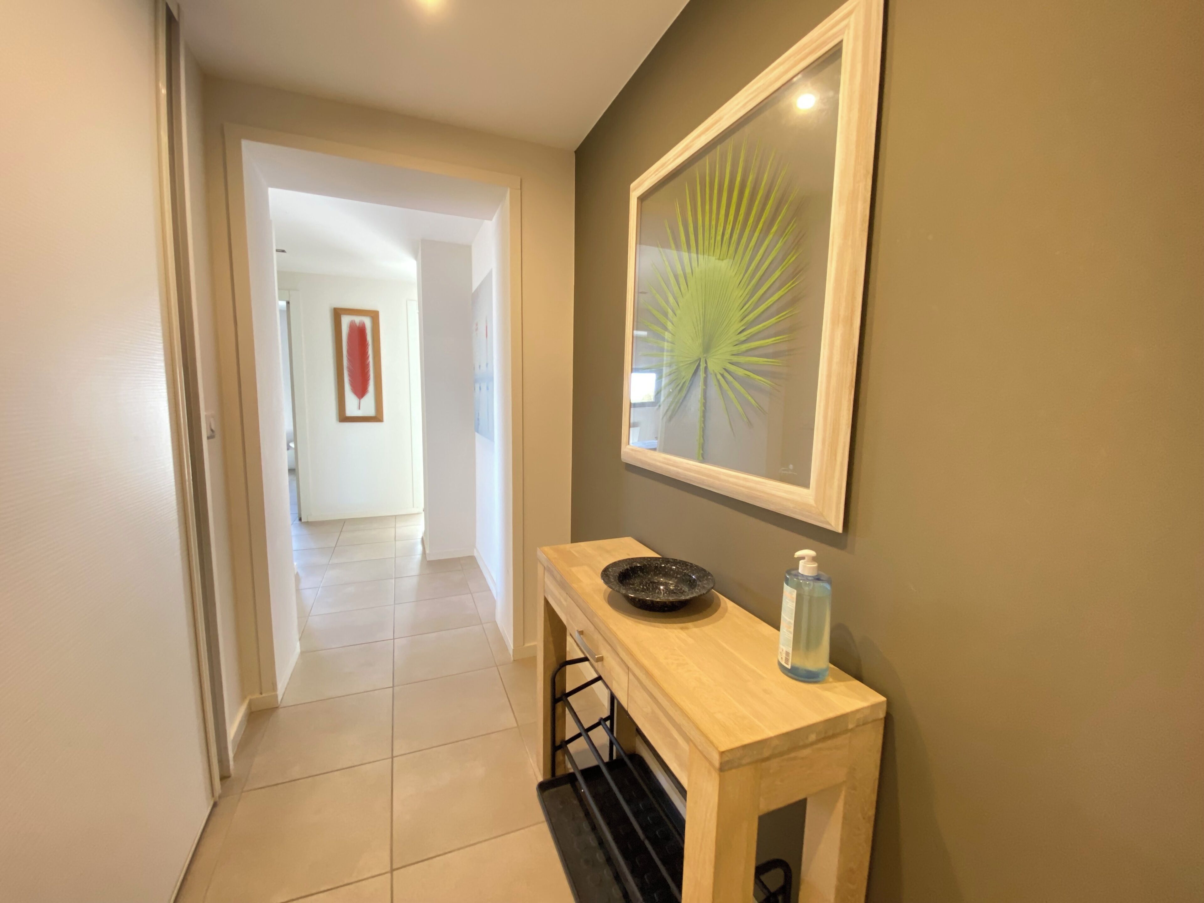 A hallway with a wooden console table, a framed artwork, and a bottle of hand sanitizer.