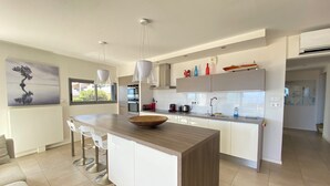 Une cuisine moderne dotée d’un îlot central, de meubles blancs et d’appareils électroménagers en acier inoxydable.