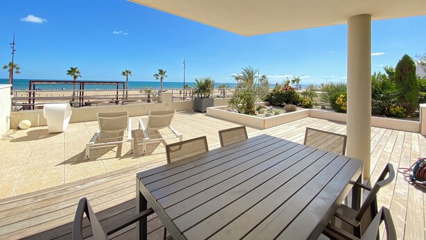 Un espace extérieur abrité, aménagé avec des sièges, et offrant une vue sur la plage et l’océan.