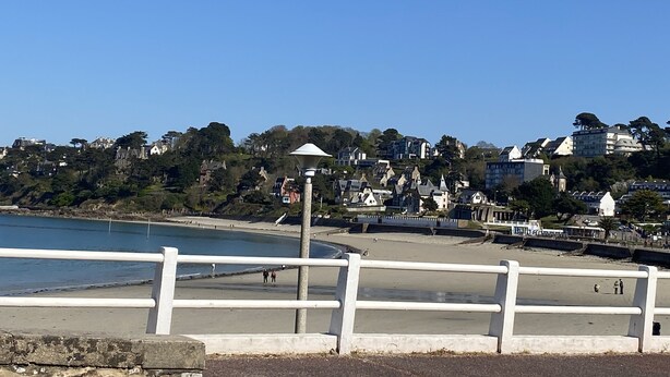 A coastal view with a white railing, a beach, and buildings in the background. - Renovated house, seaside on the port of Ploumanac'h - Perros-Guirec (Perros-Guirec)