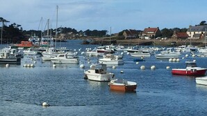 A marina with numerous boats docked, a stone wall in the foreground, and buildings in the background. - Renovated house, seaside on the port of Ploumanac'h - Perros-Guirec (Perros-Guirec)