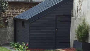 A garden with two large black planters and a wooden deck. - Renovated house, seaside on the port of Ploumanac'h - Perros-Guirec (Perros-Guirec)