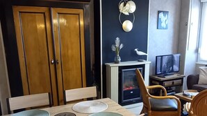 Een eethoek met een houten tafel en stoelen, een televisie en een open haard.