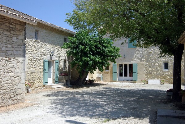 A courtyard with stone buildings, a tree, and a gravel path.