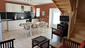 A compact kitchen with white cabinets, a dining area with a table and chairs, and a wooden staircase. - Charming furnished apartment in Mas, UzËs, pool, 656 yards away from town centre (Uzès)