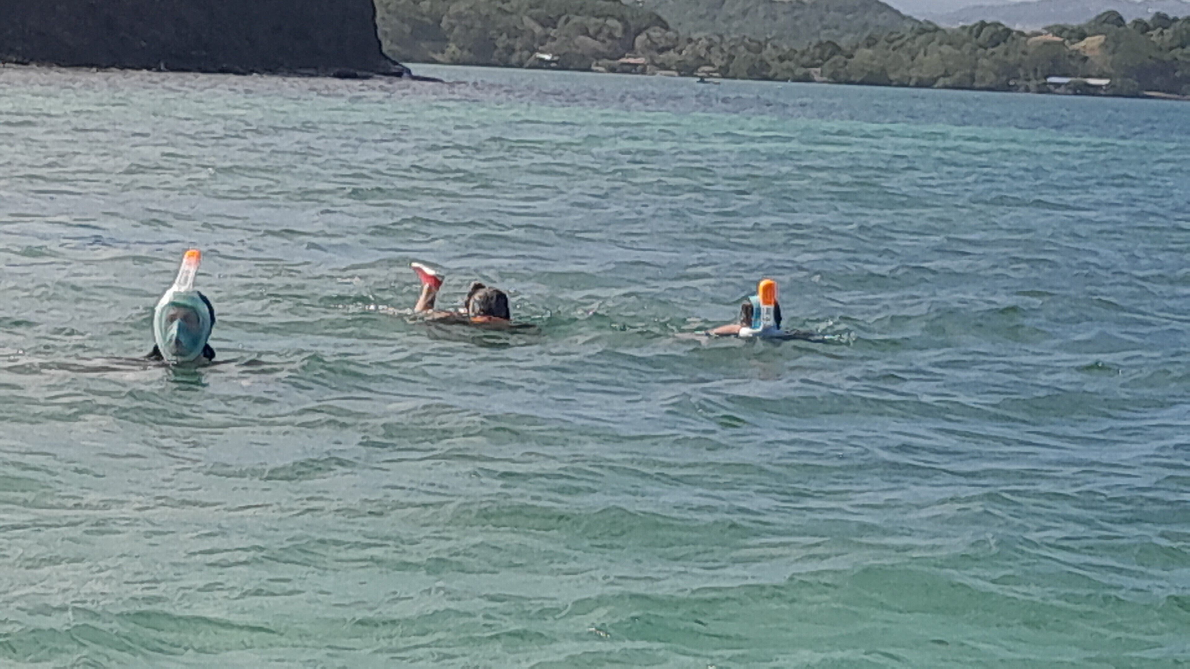 Een waterlichaam met drie mensen die zwemmen.