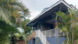 A two-story house with a balcony, surrounded by palm trees. - NEW SUITE COTTAGE F3 ANY COMFORT NEAR BEACH ANSE FIGUIER  (Rivière-Pilote)