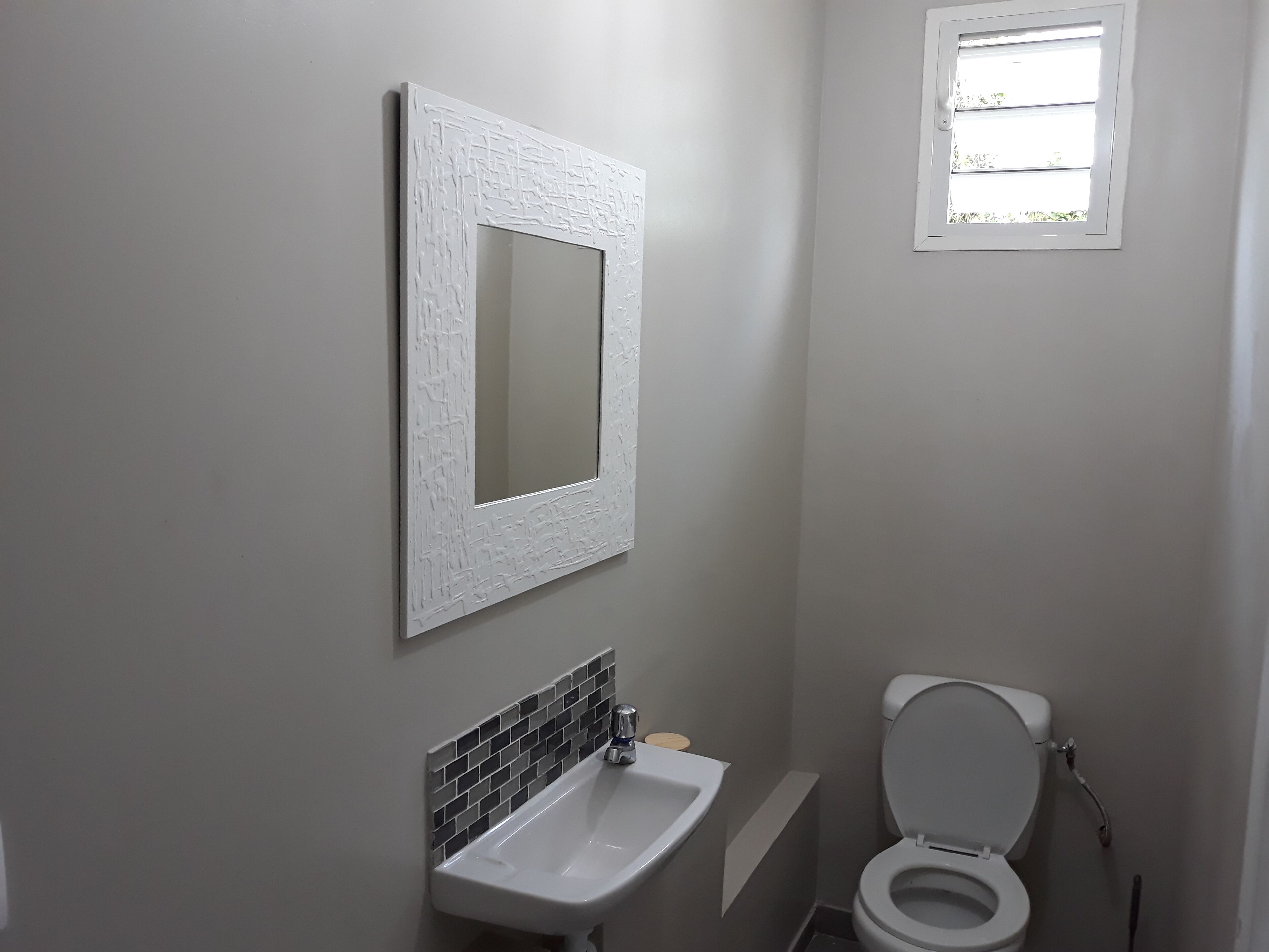 A bathroom with a white sink, a mirror, and a toilet.