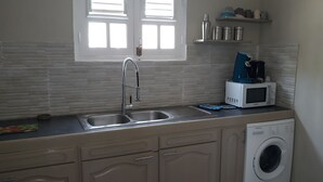 A compact kitchen with a double sink, a microwave, a coffee maker, and a washing machine. - NEW SUITE COTTAGE F3 ANY COMFORT NEAR BEACH ANSE FIGUIER  (Rivière-Pilote)