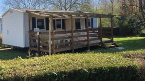 A small, single-story mobile home with a wooden deck and a covered porch. - Mobile home with air conditioning for 6 people near EUROPA PARK (Boofzheim)
