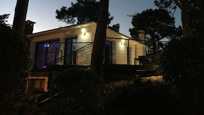 Una casa moderna con facciata in vetro, una scala e una fonte di luce a sinistra.