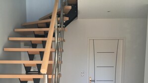 Una moderna scala con gradini in legno e ringhiere in metallo, che conduce a una porta bianca con una serratura.