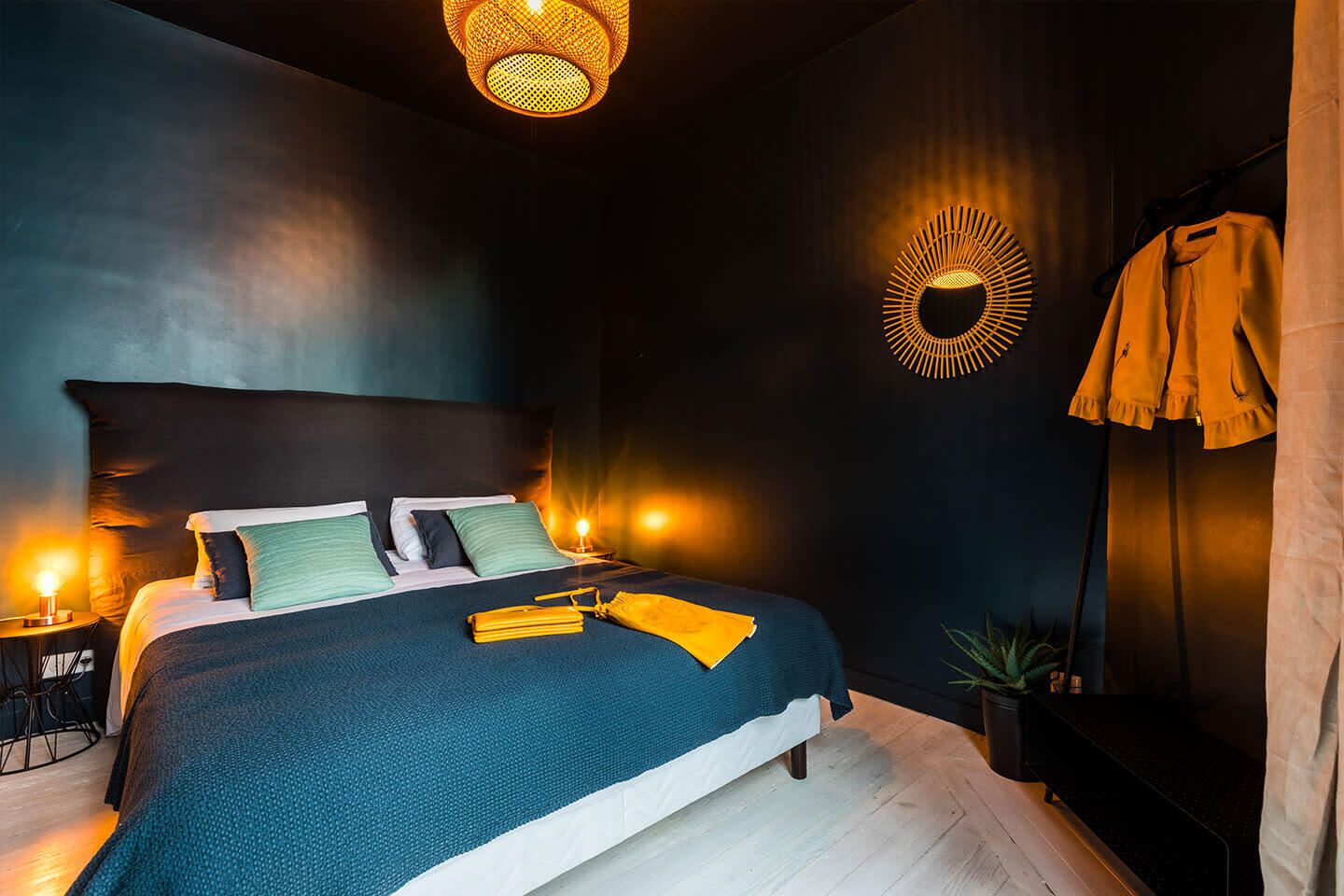 A modern bedroom with a large bed, two bedside lamps, a wall-mounted light fixture, and a hanging coat rack.