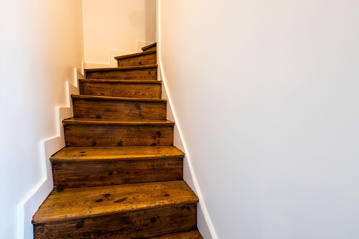 Eine Holztreppe mit weißen Wänden.