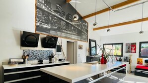 A modern kitchen with a large island, black and white cabinetry, and a cityscape mural on the wall.
