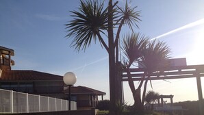 A building with a sloped roof, a staircase, and palm trees. - Appt classified 4 *, 2 swimming pools, free WIFI, terrace, bbq, edge of the marine lake (Vieux-Boucau-Les-Bains)