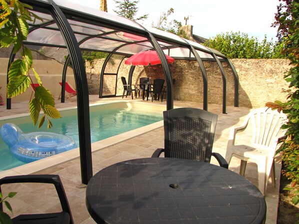 A pool area with a covered seating area, a table, and chairs. - comfortable house private indoor heated pool 28 ° C 450m sandy beaches (Santec)