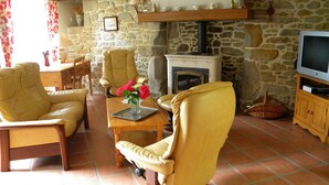 A cozy living room with stone walls, a fireplace, and yellow leather chairs. - comfortable house private indoor heated pool 28 ° C 450m sandy beaches (Santec)