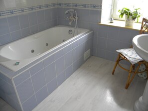 A bathroom with a bathtub, a sink, and a window with a plant. - comfortable house private indoor heated pool 28 ° C 450m sandy beaches (Santec)