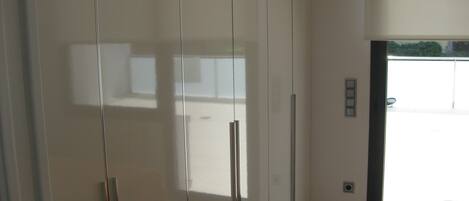 A modern room with a large wardrobe, a door leading to an outdoor area, and a tiled floor.