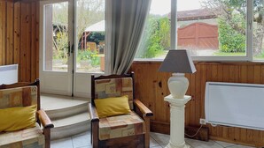 A cozy room with wooden walls and large windows, a white radiator, and two wooden chairs with yellow cushions. - Successful holiday whatever the weather (Ancy-Le-Franc)