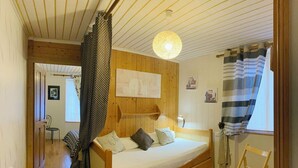 A cozy room with a wooden bed, a hanging light fixture, and a striped curtain. - Successful holiday whatever the weather (Ancy-Le-Franc)