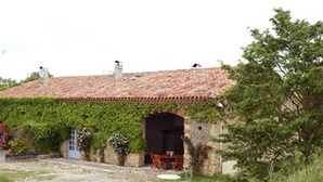 A rustic stone building with a tiled roof, ivy-covered walls, and a small outdoor seating area with chairs and a table. - Autan roses, Character Cottage in Lauragais Auriac / Vendinelle (Auriac-Sur-Vendinelle)