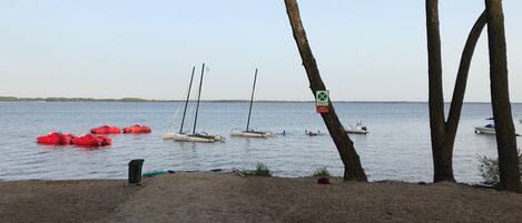 Una playa con barcos, un letrero y árboles.