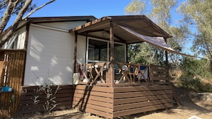 A small, single-story cabin with a wooden deck and a covered porch. - Bungalow Philippi Maurea 5 (air-conditioned )300 meters from the beach. (Belvédère-Campomoro)