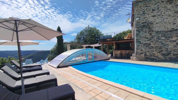 A swimming pool with lounge chairs and umbrellas, a stone building, and a view of the hills. - Gîte 12 pers, pétanque court, swimming pool : week from july 11th to 18th free ! (Courris)