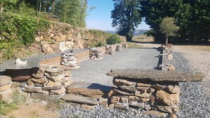 A stone pathway leading through a garden with a rustic stone bench and a small table. - Gîte 12 pers, pétanque court, swimming pool : week from july 11th to 18th free ! (Courris)