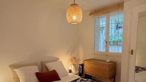 A bedroom with a bed, bedside table, lamp, window, and a door.