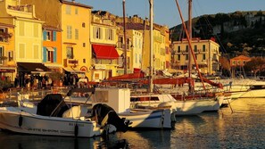 A marina with boats docked, buildings with balconies, and a hillside in the background. - Cassis, downtown: "La Rade" apartment, behind the harbor, nice view, and parking (Cassis)