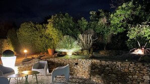 An outdoor patio area with stone walls, a seating arrangement, and various plants.