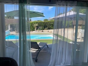 Un espace extérieur abrité comprenant une piscine, un fauteuil de relaxation et une table.