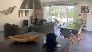 A modern kitchen with a large island, dining area, and a view of the outdoors.